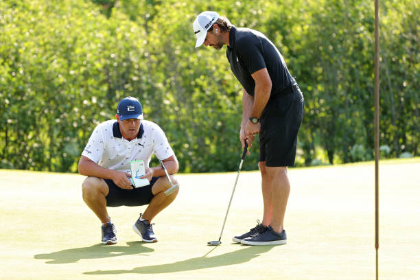 Bryson DeChambeau using a StrackaBook to read a putt for Aaron Rodgers